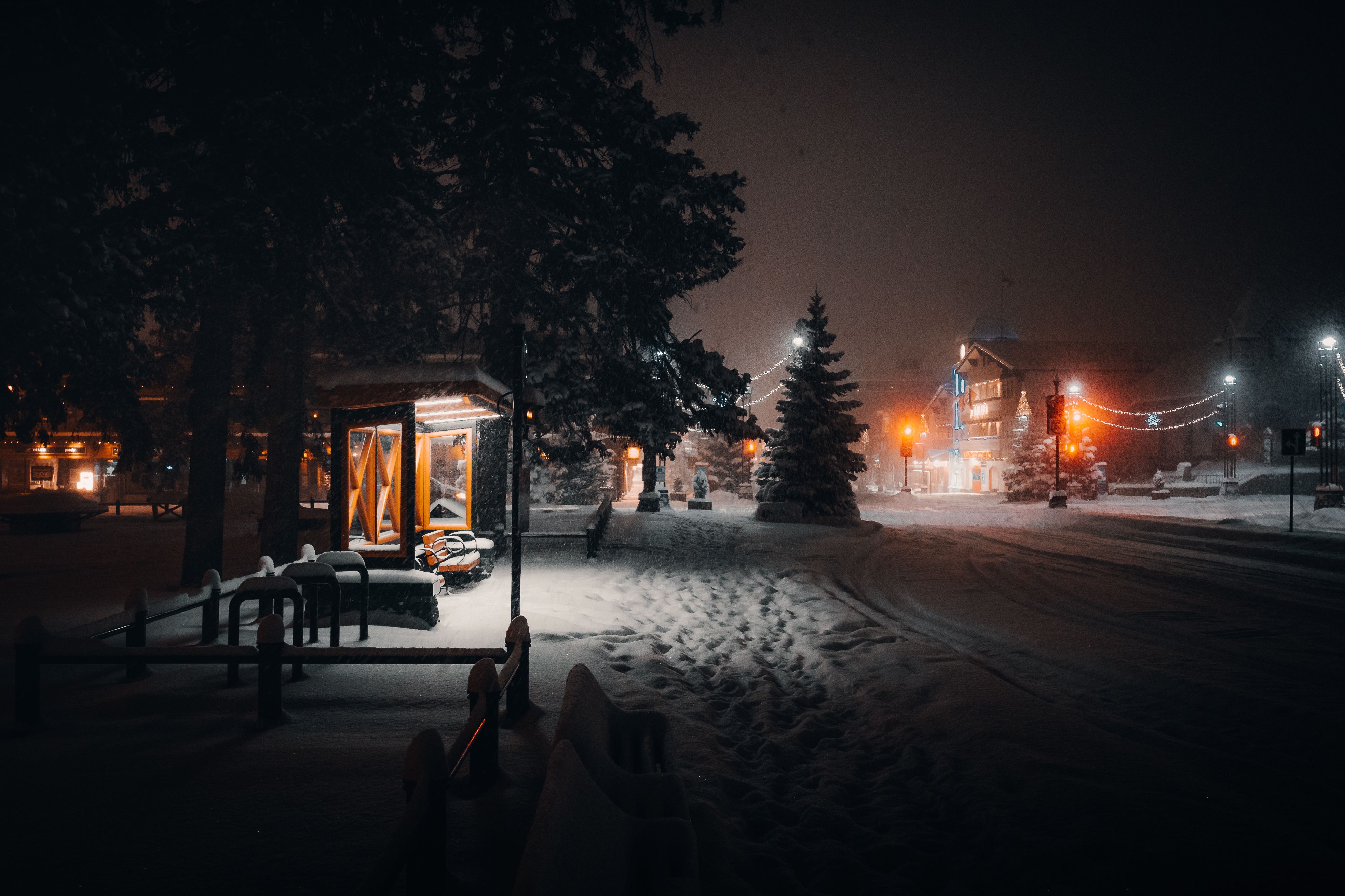Snow-covered street glowing with festive Christmas lights on a quiet winter night in town