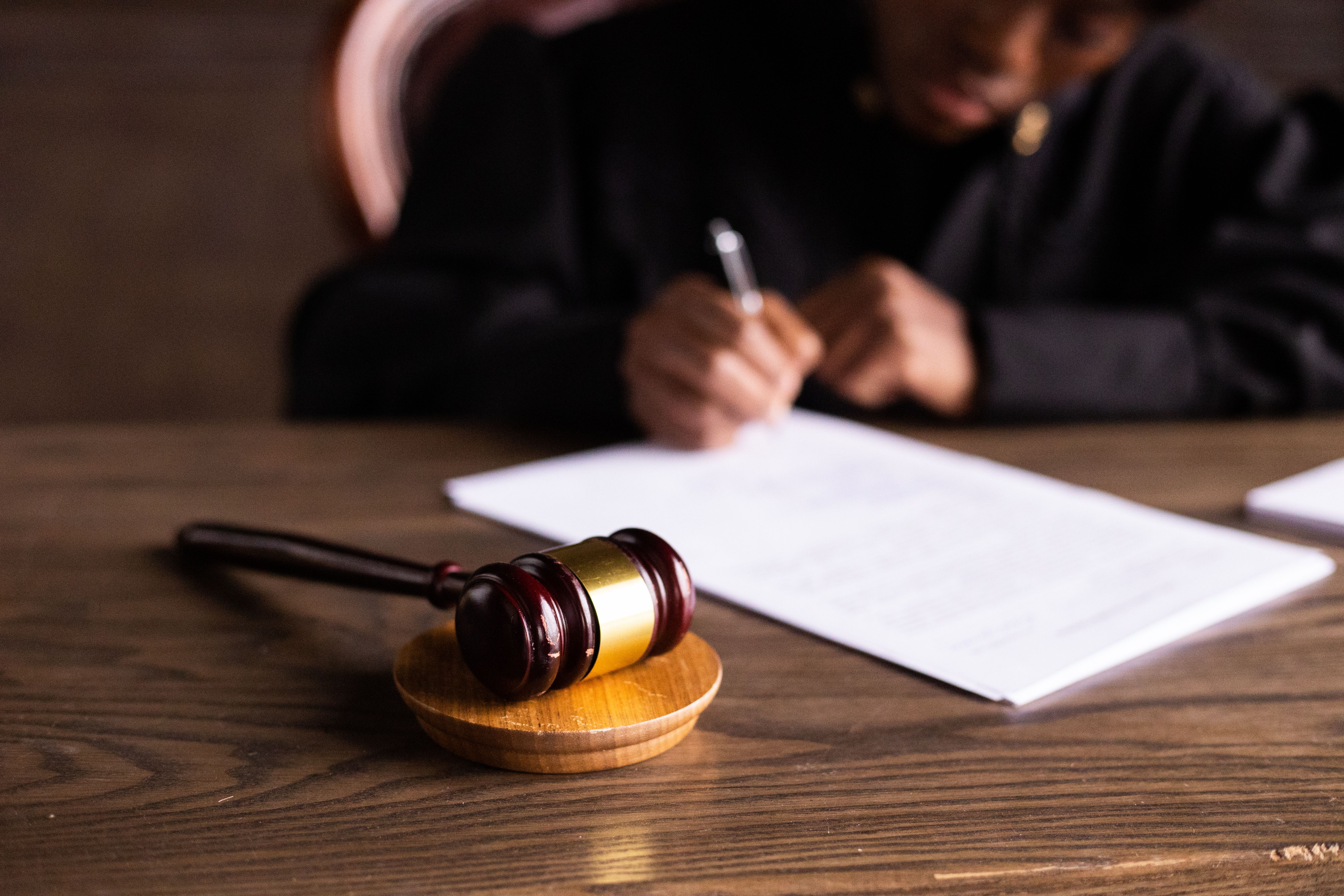 Judge signing documents beside a gavel, representing legal oversight and accountability.