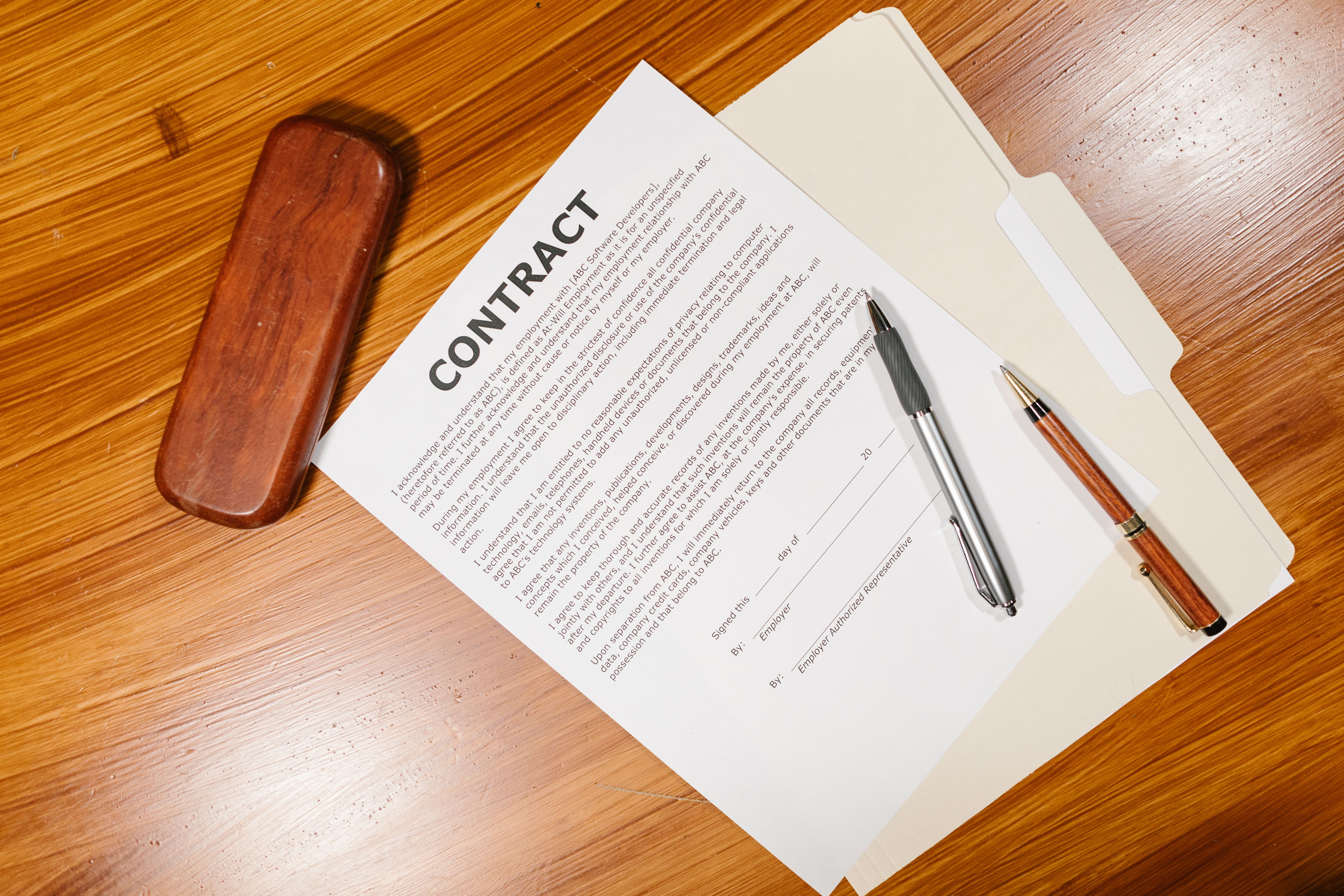 Contract document with pens and a briefcase on a wooden table, illustrating the importance of reviewing funding terms.